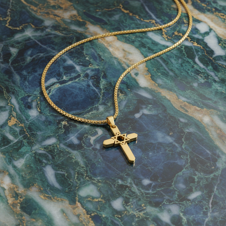 Gold necklace with a cross pendant on a green marble surface