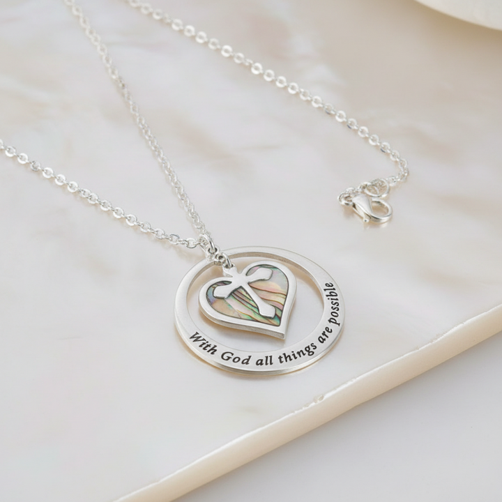 Silver necklace with heart-shaped pendant and engraved text on a light background